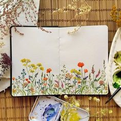 an artist's notebook with watercolors and flowers on it next to other art supplies