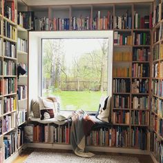 a room filled with lots of books on top of a book shelf next to a window