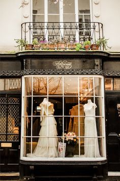 a store front with mannequins in the window and flowers growing out of it