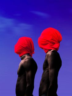 two men with red turbans on their heads standing in front of a blue sky