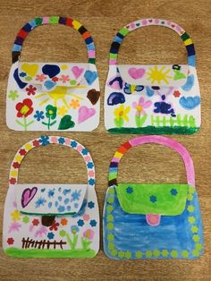 four handbags made out of paper on a wooden table with flowers and hearts painted on them