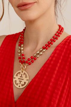 a woman wearing a red top and necklace with a gold medallion on the front of her neck