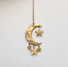 a gold necklace with stars hanging from it's side on a white wall background