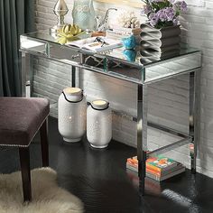 a glass desk with two vases on it and a chair next to it in front of a brick wall