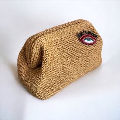 a brown purse with an eye on the front and red eyes on the inside, sitting on a white surface