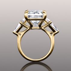 Expressive and imbued with meaning, this ring makes a statement with its effervescent trio of diamonds. It bears an emerald-cut diamond center stone, in between two kite-cut diamonds on v-shaped prongs. The three stones represent the past, present, and future of a love journey are supported by the graceful curves of a trellis, which also adds interest to the ring's side face. Luxury Emerald Ring With Square Cut Diamond, Luxury Square Cut Diamond Emerald Ring, Luxury Square-cut Emerald Ring With Diamonds, Luxury Square Cut Emerald Ring With Diamonds, Formal Octagon Diamond Ring With Accents, Luxury Three Stone Octagon Ring, Luxury Diamond Cut Emerald Ring, Luxury Trillion Cut Emerald Ring For Formal Occasions, Modern Octagon Emerald Ring With Diamond