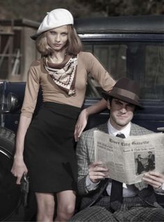 a man and woman sitting on the back of a car while reading a newspaper together