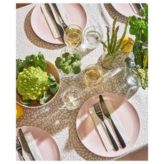 a table topped with pink plates filled with food and veggies next to utensils