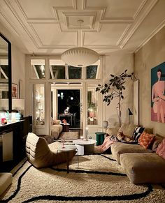 a living room filled with lots of furniture and art work on the wall above it