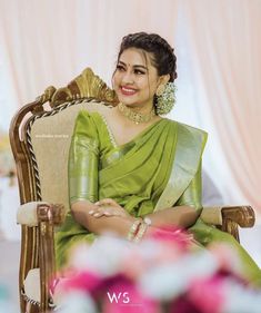 a woman in a green sari sitting on a chair