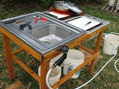 an outdoor cooking table with pots and pans sitting on it's side in the grass