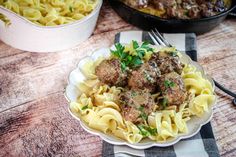 pasta with meatballs and parsley in a white bowl on a checkered tablecloth