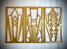 three pieces of art made out of wood with geometric designs on the wall behind them