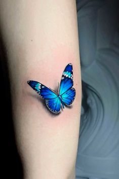 a blue butterfly tattoo on the arm