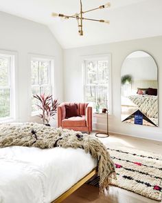 a bedroom with a bed, chair and mirror