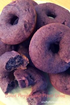 a pile of purple donuts sitting on top of a white plate