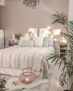 a white bed sitting next to a tall plant in a bedroom under a chandelier