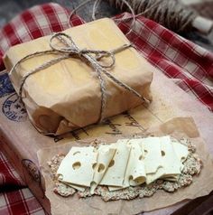 two pieces of cheese tied up on top of a piece of brown paper next to a wrapped package