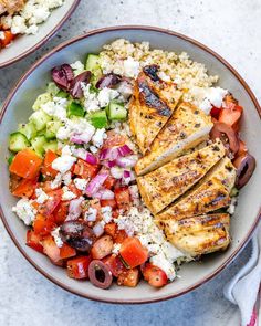 two bowls filled with chicken and vegetables on top of a white countertop next to each other