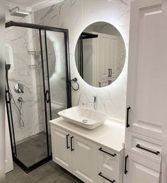 a bathroom with a sink, mirror and shower stall in the corner on the wall