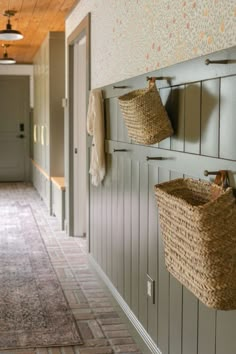 two baskets are hanging on the wall next to some hooks and towel racks in a hallway