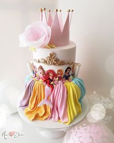 there is a white cake with princesses on it and decorations around the bottom tier