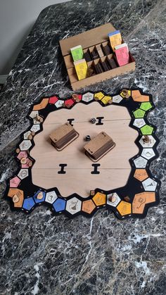 a game board with pieces of chocolate on it and a box of candy in the background