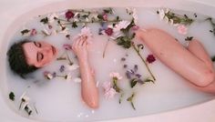 a woman laying in a bath filled with flowers