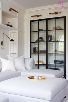 a white couch sitting in front of a book shelf next to a glass case filled with books