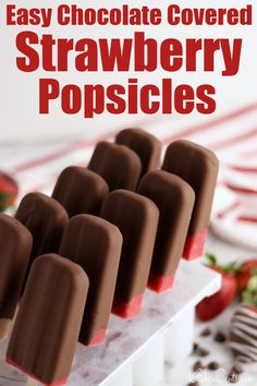 easy chocolate covered strawberry popsicles on a white tray with strawberries in the background