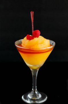 a dessert in a glass bowl with raspberries on the top and another fruit garnish