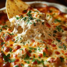 a wooden spoon scooping out some cheese from a casserole dish