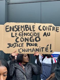 a group of people holding up signs in front of a building with writing on them