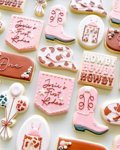 many decorated cookies are displayed on a white surface with pink and red decorations, including boots, hearts, flowers, and balloons