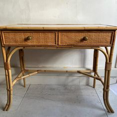 a wicker desk with two drawers is shown in front of a white wall and floor