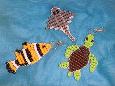 three beaded sea animals are on a blue cloth covered surface, one has a fish and the other is a turtle