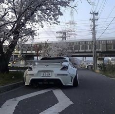 a white sports car is parked on the side of the road in front of a bridge