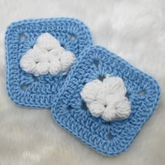 two crocheted blue squares with white flowers on them