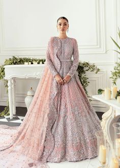 a woman in a pink and silver wedding gown standing on a white floor next to a fireplace