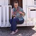 a woman sitting in the doorway of a white dog house