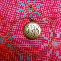 "Beautiful example of a classical monogrammed locket from the Edwardian era. Three letters are hand-engraved at the front of the locket, the back is plain. I read \"TOS\" but the first letter is ambiguous. Details: The locket is from the 1910s. I believe it is made of gold filled. It is in excellent condition, very little surface wear and no dent. Inside there is a symbol, probably the maker mark, which represents a flower with two leaves. It opens from the top, and shuts tightly with a snap. In The Edwardian Era, Gold Locket Necklace, Gold Locket, Edwardian Era, The Maker, Seed Pearl, Heart Locket, Locket Necklace, Hand Engraving