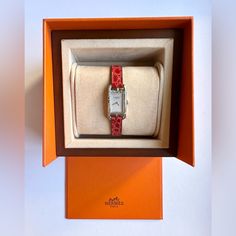 This Herms Nantucket Jet De Diamants Ladies Watch Features A Silver Dial With 55 Diamonds And A Quartz Movement. Its Case Is Made Of Polished Stainless Steel With A Silver Color, And It Has A Red Leather Band With A Maximum Wrist Size Of 5.3-6.2 Inches. This Luxury Wristwatch Has A Rectangular Shape And A Case Width Of 17mm And Height Of 29mm. It Is Suitable For Both Casual And Formal Wear And Has A Classic Style. Please Note Small Scratch On The Inside Of The Watch, Above The Herms Crest. The Reference Number Is W045247ww00. Timeless Red Watch With Rectangular Dial, Timeless Red Watches With Rectangular Dial, Modern Red Rectangular Watch Accessories, Luxury Red Watch With Tachymeter, Hermes Accessories, Polished Stainless Steel, Ladies Watch, Nantucket, Leather Band