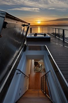 the sun is setting over the water and there are stairs going up to the deck