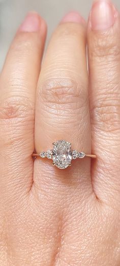 a woman's hand with a diamond ring on top of her left hand,