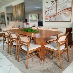 a dining room table and chairs in front of a painting