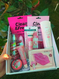 a person holding up a pink box filled with beauty products and other items in it