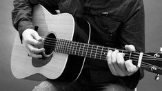 a man is playing an acoustic guitar in black and white