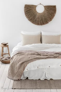 a bed with white linens and pillows in a room next to a wooden chair