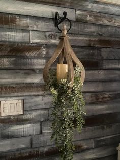 a candle hanging from the side of a wooden wall next to a planter with greenery on it