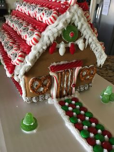 a gingerbread house decorated with candy canes and pretzels for the roof